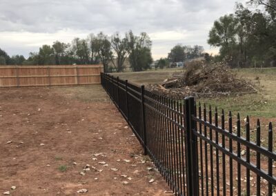 A fence being constructed in the dirt, showing the early stages of its installation.