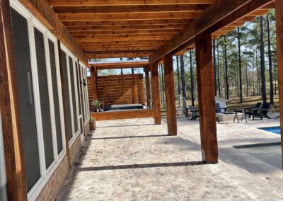 A wooden pergola shading a patio next to a pool.