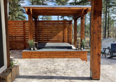 A wooden pergola covering a hot tub on a patio.