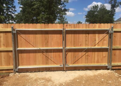 A wooden fence with a metal gate in a garden.