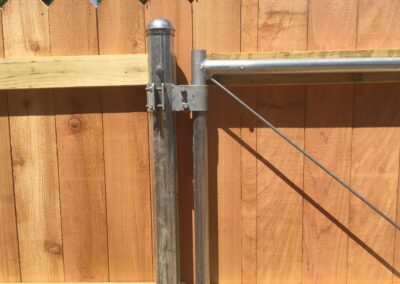 An image of a wooden fence and metal gate in a backyard.